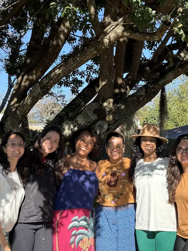 Participantes do Retiro Prāṇa Veadeiros 2025 juntas embaixo de uma árvore antiga